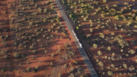 toma aérea de un camión de carga que conduce por una carretera rural en el desierto australiano durante la puesta de sol - cámara lenta