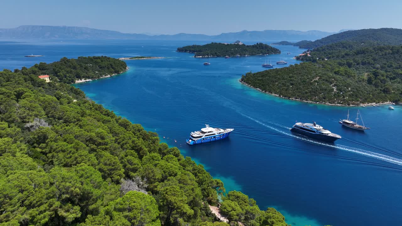 Yacht e barche navigano attraverso acque turchesi vivaci tra isole boscose vicino a Mljet, Croazia. Carrellata in avanti al rallentatore.