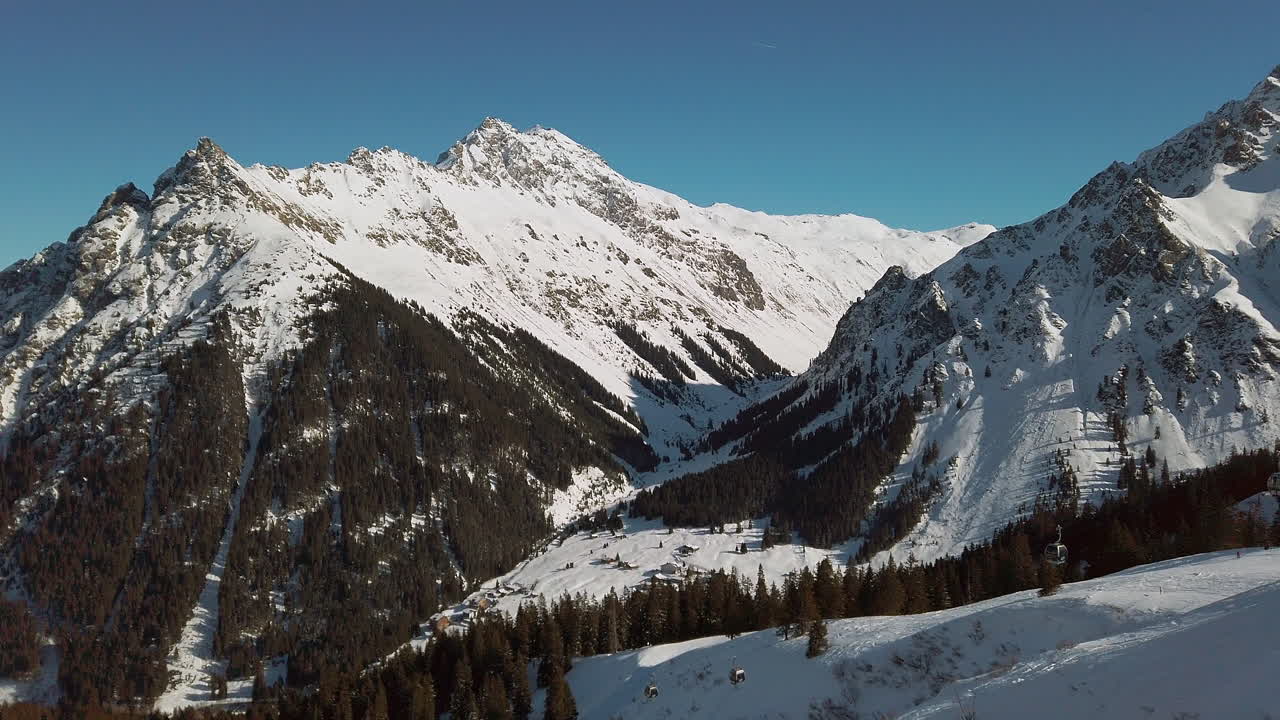 Montafon Sıradağları'nın altındaki karla kaplı yamaçlarda kayakçıları taşıyan yalnız bir telesiyej, Avusturya Alpleri, yavaş çekim.