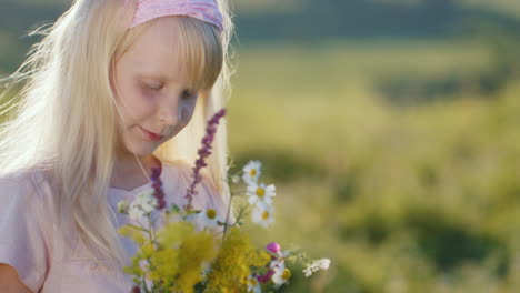 cute little girl enjoying nature looking at bouquet of wildflowers