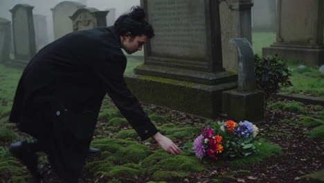 a woman placing flowers at a cemetery in foggy weather