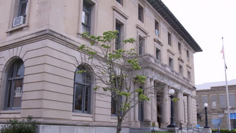 a slow tilt down establishing shot of the entrance to a grand bank or government building in a small town