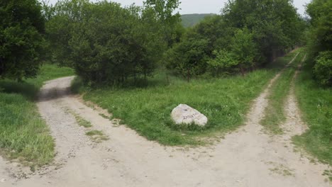 Retreating-drone-shot-of-a-rock-landmark-in-the-middle-of-a-crossroad-located-in-the-woodlands-of-Tsarichina-Hole-village-in-Bulgaria