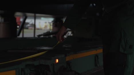 Close-up-of-a-man-standing-in-a-dark-spot-measuring-a-lorry-with-a-ruler