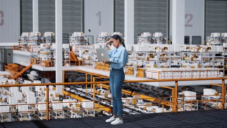 woman working in a warehouse using a laptop