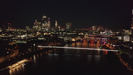 Aerial-night-view-of-large-town-lit-by-thousands-of-lights.-Forwards-fly-towards-group-of-skyscrapers-in-City-financial-district.-London,-UK