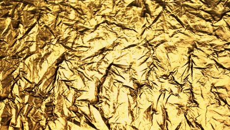 crumpled, golden foil shining in the soft spotlight. interesting, endless, seamless, abstract pattern of precious glossy metal looking luxurious and expensive. perfect background graphic.