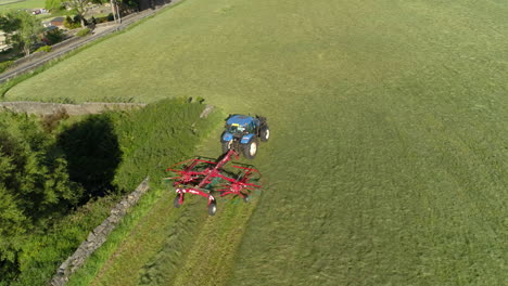 drone tracks a farmer working his land in a blue tractor in a beautiful green west yorkshire farm during the day, aerial