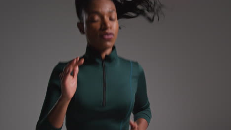 Close-Up-Shot-Of-Female-Athlete-Wearing-Tracksuit-Training-In-Gym-Fitness-Class-Running-On-The-Spot-Against-Plain-Background-1