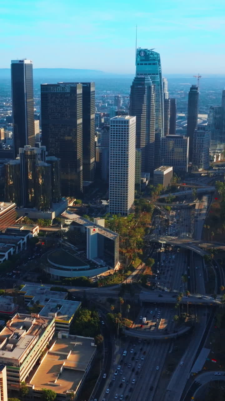 Approaching the beautiful modern skyscrapers of contemporary Los Angeles. Lively downtown at sunny daytime from aerial perspective. Vertical video