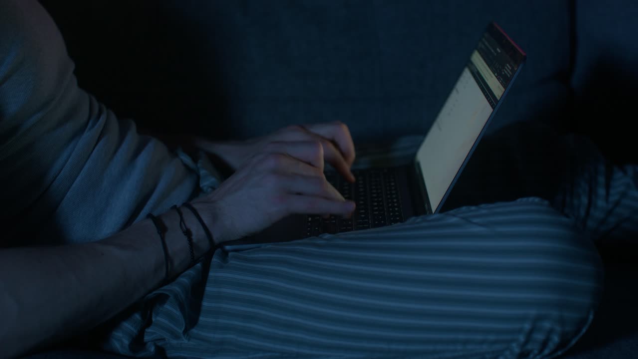 Persona che usa un laptop di notte su un divano
