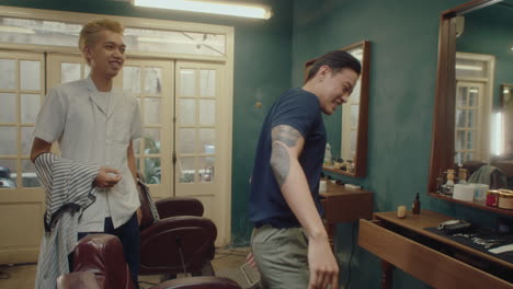 cheerful asian barber greeting customers at the barbershop
