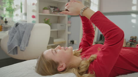 Teenage-girl-wearing-orthodontic-braces-lying-on-bed-at-home-talking-on-mobile-phone-and-smiling---shot-in-slow-motion