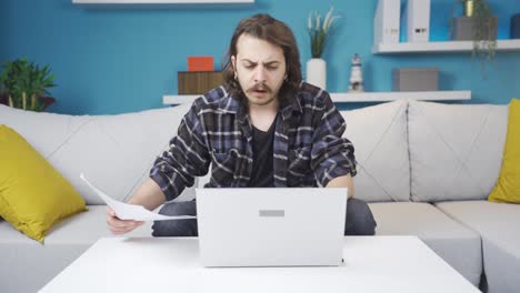 hombre comparando el papeleo con la computadora, confundido. tiene una expresión facial negativa.