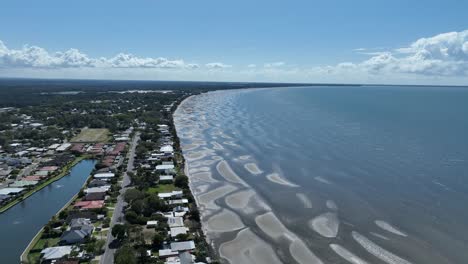 Drone-Aéreo-Disparado-Sobre-La-Playa-De-Beachmere-Y-Bancos-De-Arena,-Barcos-En-El-Río-Que-Se-Abre-Hacia-La-Bahía-De-Moreton-Del-Océano