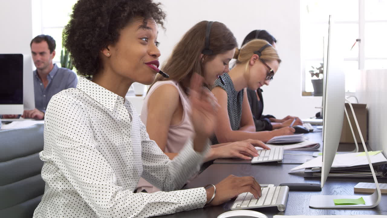 A row of women using phone headsets in an open plan office