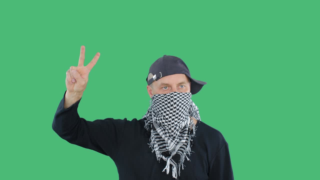 Protester hiding face and showing victory sign during riot