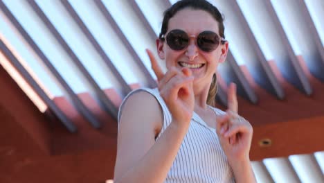 happy smiling woman wearing round sunglasses dancing feeling joy