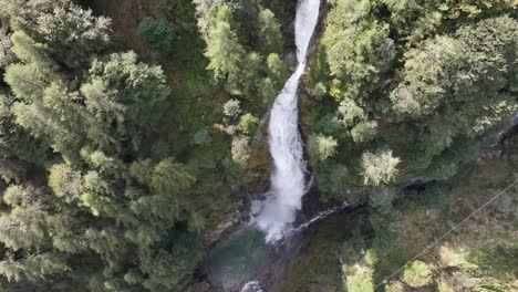 Vista-Aérea-De-Una-Alta-Cascada-En-Medio-De-Un-Bosque-Verde