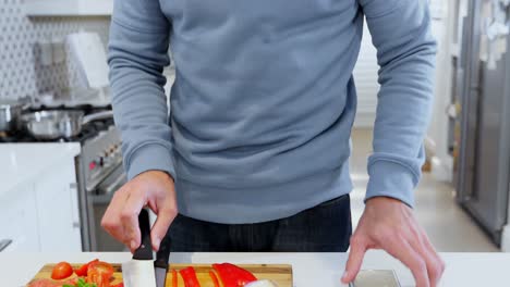 hombre feliz usando teléfono móvil mientras corta verduras 4k