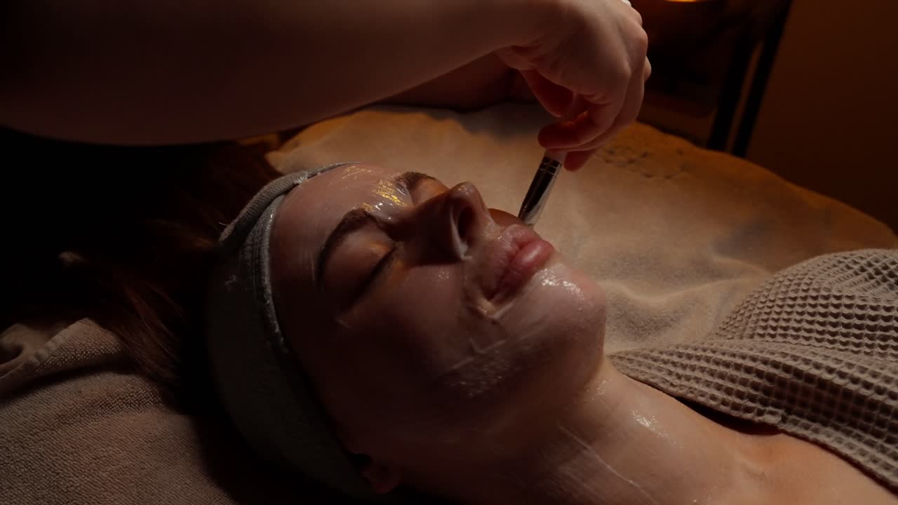 Kosmetyczka nakładająca maskę na twarz kobiecie w spa