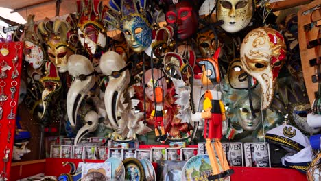 Tilt-down-of-souvenir-shop-items-including-Venetian-masks,-Rialto-market