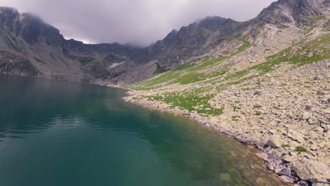 fpv drone footage of a serene mountain lake in slovakian high tatras during cloudy weather