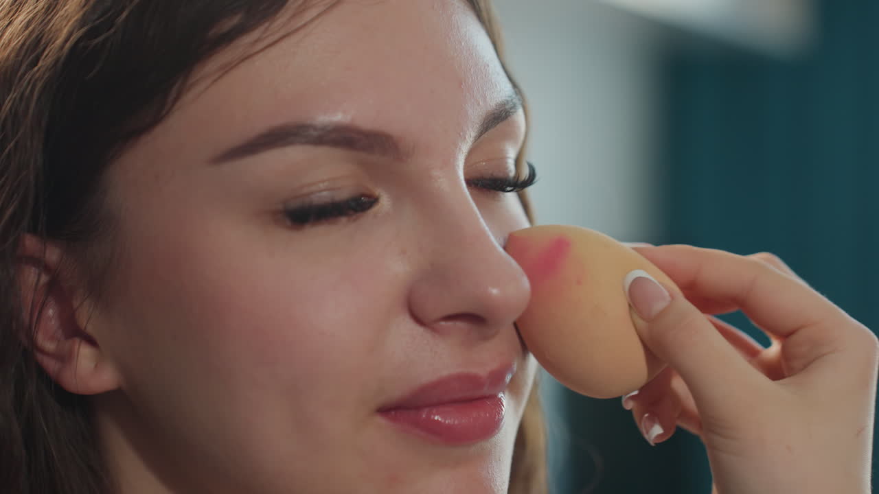 CloseUp White Woman Blending Foundation With Sponge, Beauty Influencer Testing Texture And Glow In Natural Window Light Soft Smile, Gentle Strokes, Satin Skin Finish, Calm Morning Routine