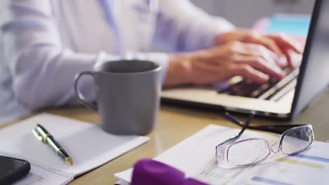 Senior-caucasian-woman-sitting-at-table-in-kitchen,-using-laptop