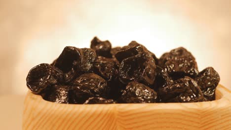 dried fruit small black plum in a plate of wood rotates slowly. loop video, close-up. 4k