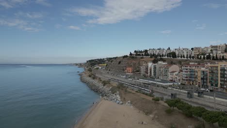 drones aéreos vuelan sobre la estación de tren junto al mar, en la costa de arenys de mar cataluña españa, playa, horizonte, avenida y arquitectura de la ciudad