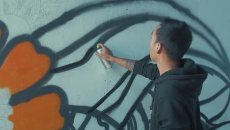 young male graffiti artist spraying design on wall