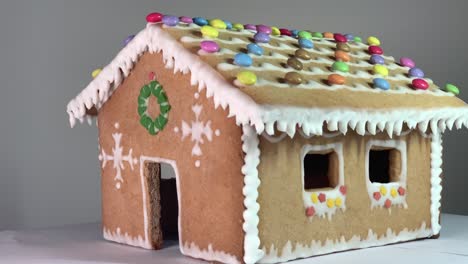 revelación de una casa de pan de jengibre hecha con miel y harina con adornos navideños con dulces y nieve blanca como decoración