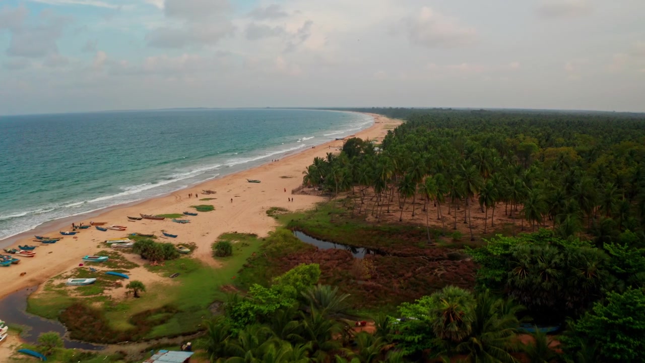 Vista aérea de drone da Praia de Kalkudah no Sri Lanka, capturando pescadores e barcos de madeira ao longo da costa brilhante na hora dourada.