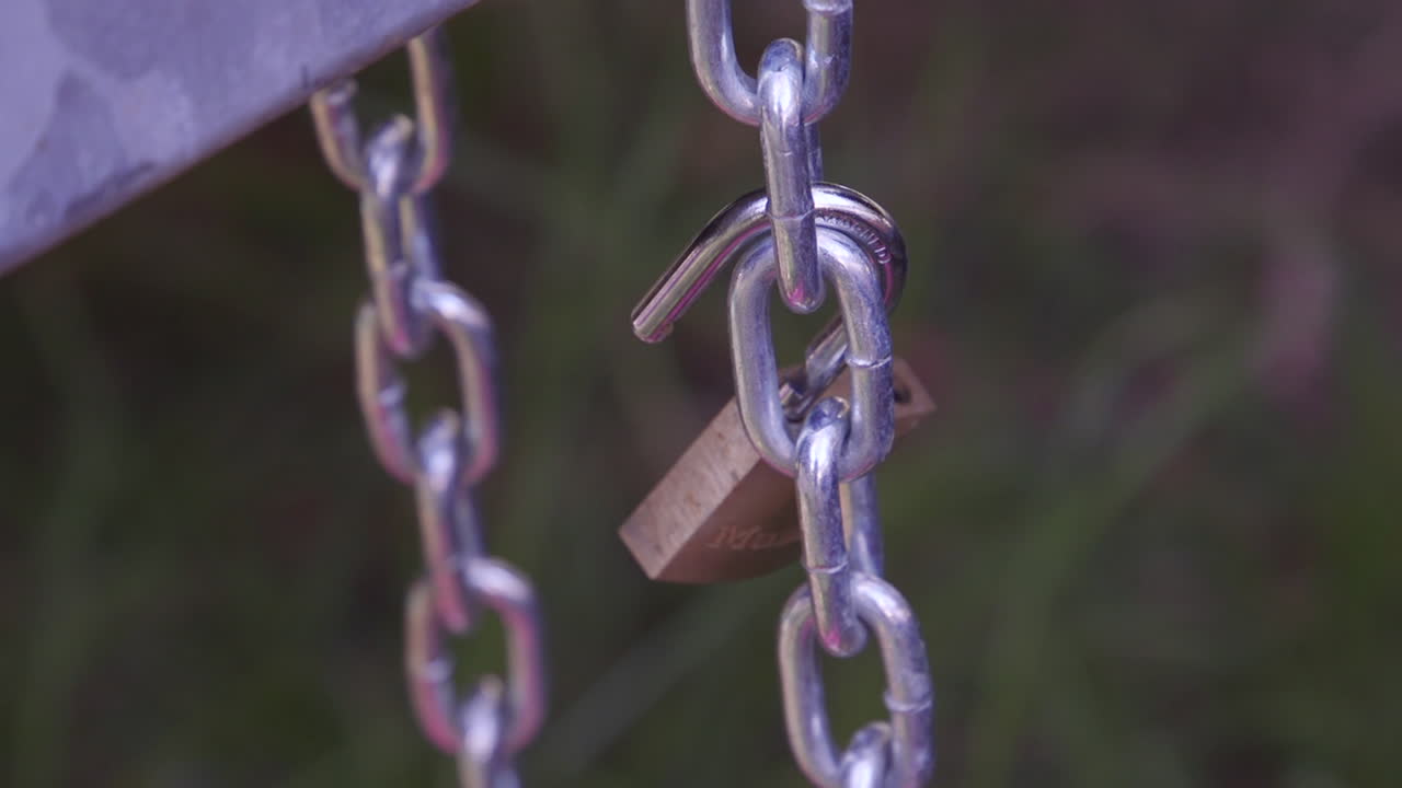 un candado abierto de color dorado y una cadena plateada entrelazados