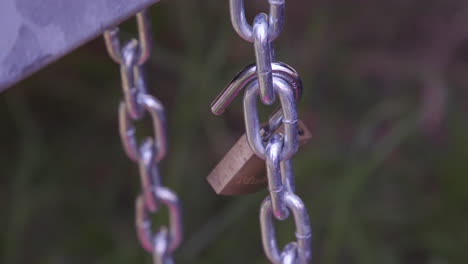 An-open-gold-coloured-padlock-and-silver-chain-interlocked-together