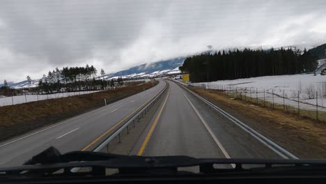 Viajando-Por-Una-Pintoresca-Carretera-Invernal,-Pasando-Bajo-El-Puente-De-Arco-En-Noruega