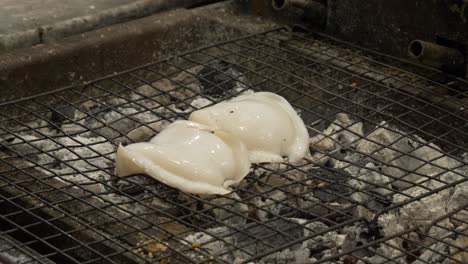 cocinar sepia a la parrilla en carbón caliente en el mercado nocturno de tailandia