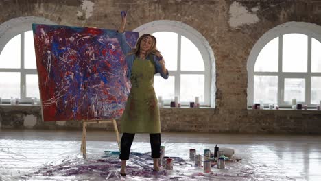 mujer bailando en un estudio de arte en cámara lenta, fingiendo cantar al micrófono