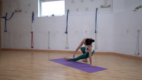 flexible woman performing three legged downward facing dog pose indoors