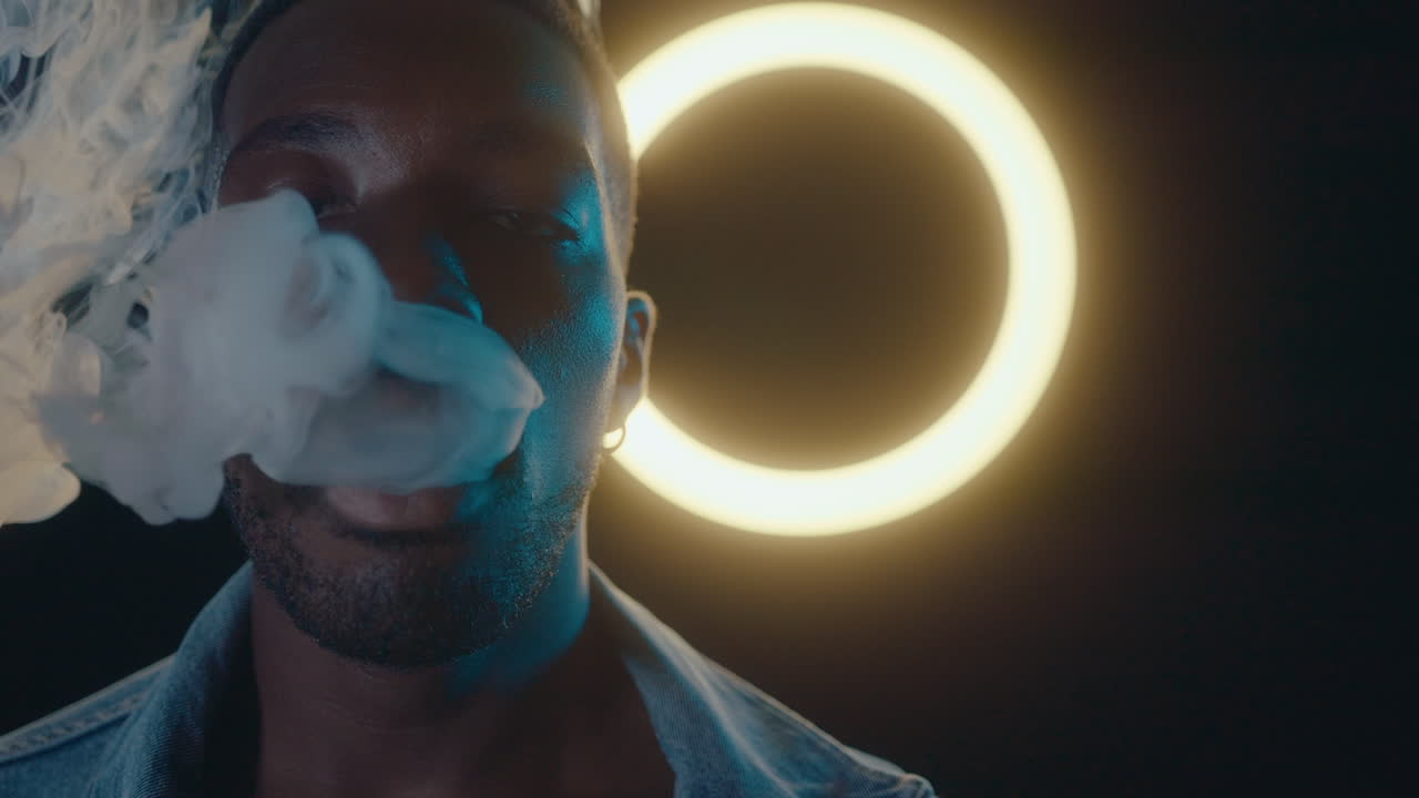 Black Man Breathing Out Vape Smoke against Ring Light