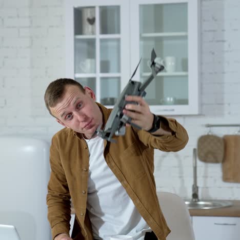 young man showing drone. man playing with professional drone in room