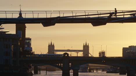 pedestrian jogging across the millennium bridge in early morning in london, united kingdom