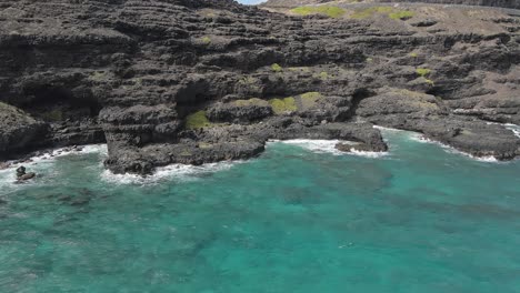 Aerial-view-of-waves-splashing-on-rock-cliffs-on-a-sunny-day-panning