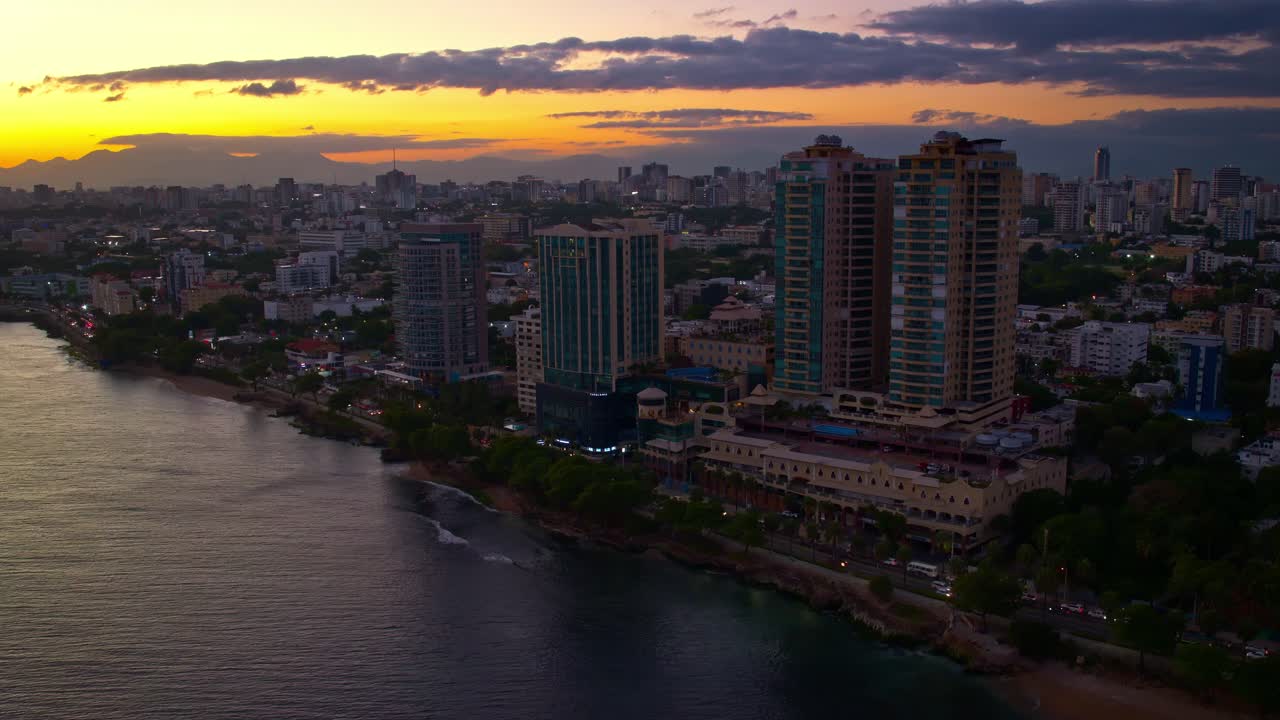 vista aérea de drones sobre rascacielos frente al mar a lo largo del malecón al atardecer, santo domingo en república dominicana