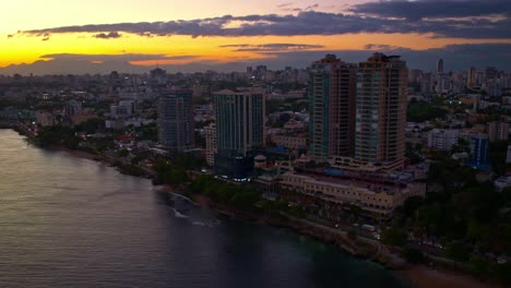 aerial drone view over seafront skyscrapers along malecon at sunset, santo domingo in dominican republic