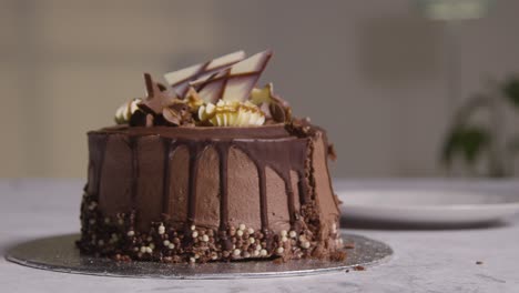 close up shot of person at home cutting slice from chocolate celebration cake on table 1