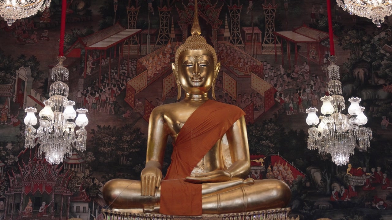 Close-up shot of a golden Buddha statue draped in an orange robe inside Grand Palace in Bangkok, Thailand