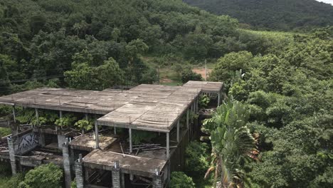 aerial backwards dolly shot of derelict abandoned building on a tropical island with palm trees