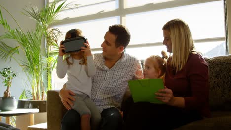 niña usando una tableta digital con sus padres en el sofá en casa 4k